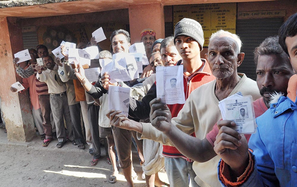 People show their voter cards as they stand in queue to cast their votes in the third phase of Jharkhand Assembly Elections in Ranchi.