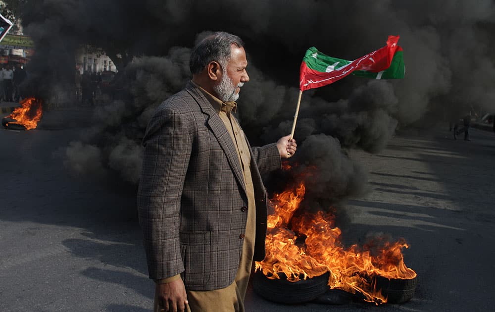 A supporter of Imran Khan's Pakistan Tehrik-e-Insaf party holds a party flag during a protest in Lahore, Pakstan.