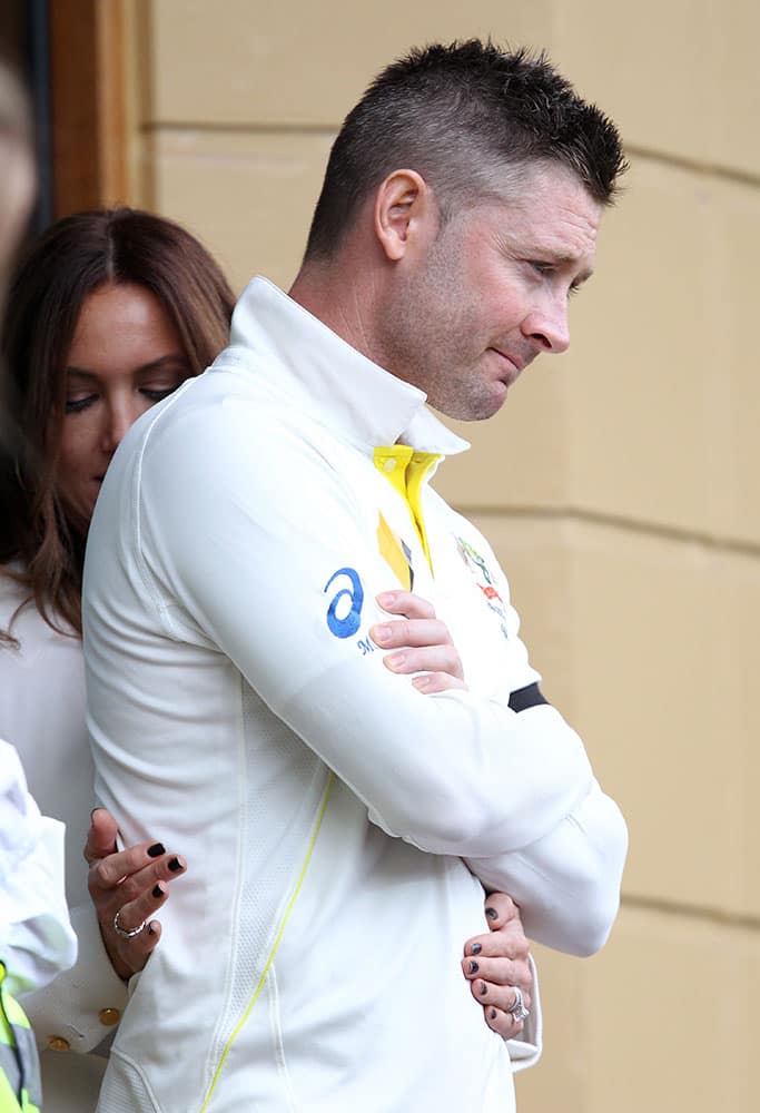 Australia's captain Michael Clarke receives attention to his back from his wife, Kyly, during a rain delay during the second day of their cricket test match against India in Adelaide, Australia.