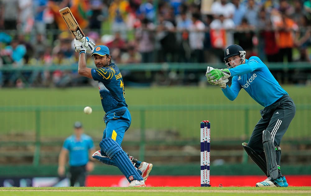 Sri Lankan batsman Kumar Sangakkara plays a shot as England's wicketkeeper Jos Buttler watches during the fifth one day international cricket match between Sri Lanka and England in Pallekele, Sri Lanka.