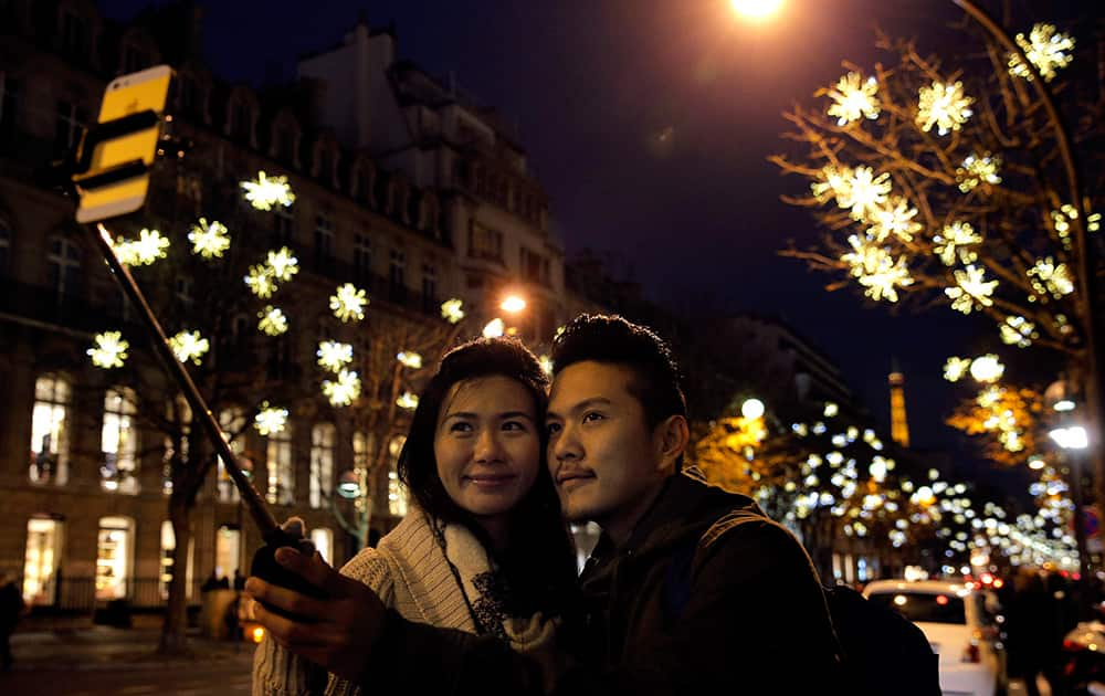 Visitors take selfies next to illuminated decorations on the Champs Elysees, in Paris.