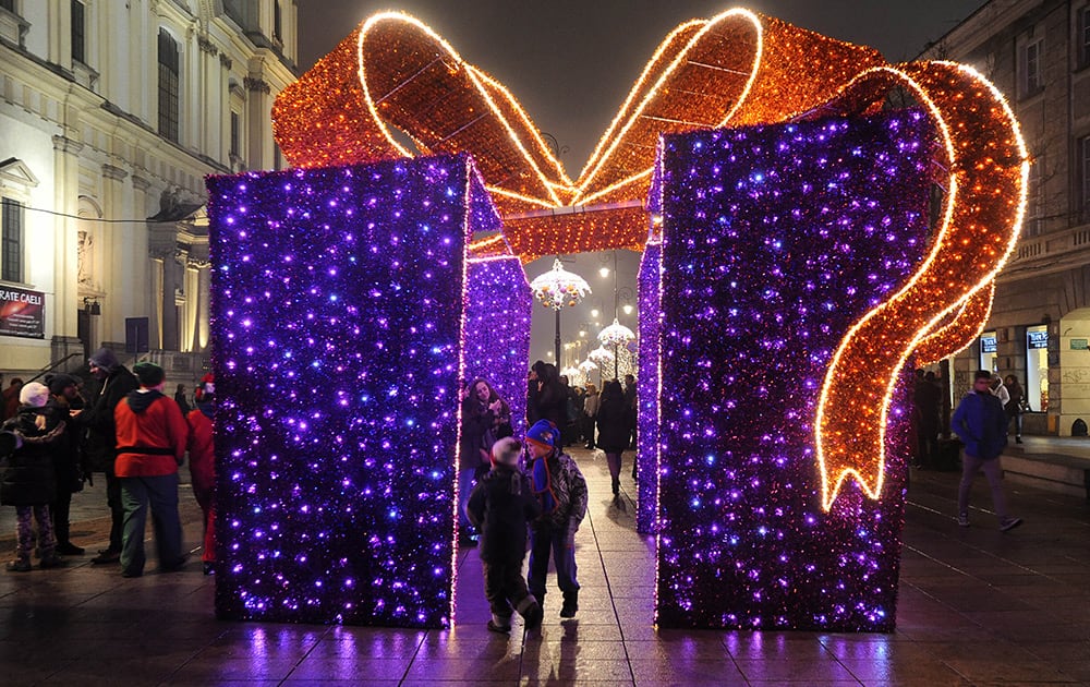 People walk past Christmas decorations on a street in Warsaw, Poland.