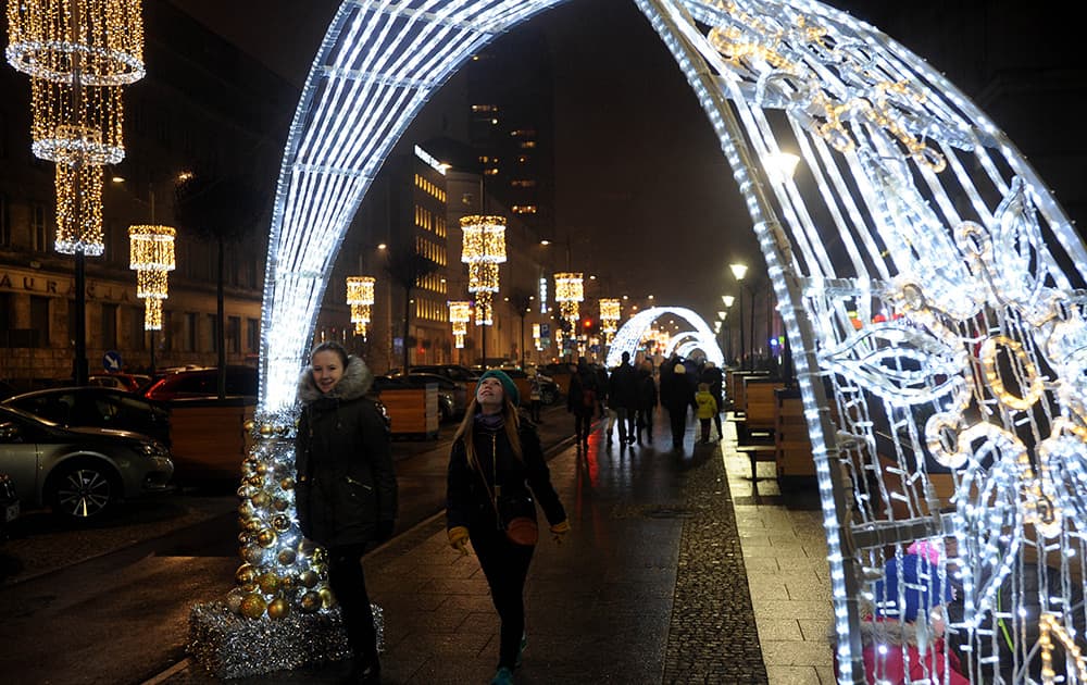 People walk past Christmas decorations on a street in Warsaw, Poland.