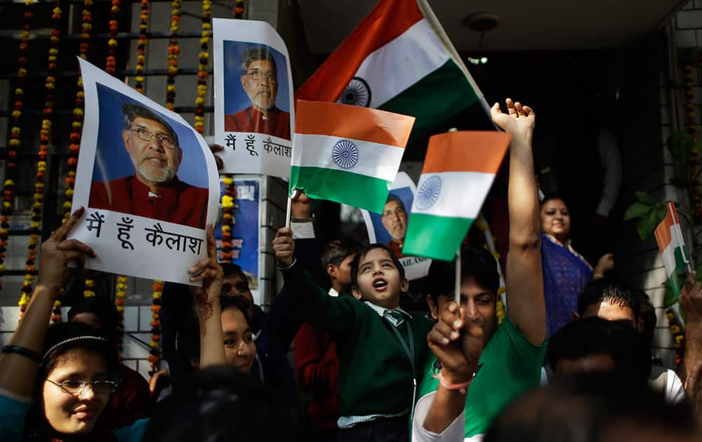 Workers and rescued child laborers at the Bachpan Bachao Andolan, or Save the Children Movement, founded by India's Nobel laureate Kailash Satyarthi wave the Indian flag and display Satyarthi's photographs as they celebrate at the organization's office in New Delhi.