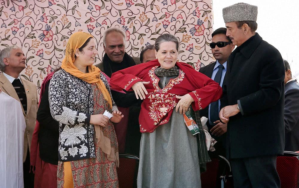 Congress President Sonia Gandhi wears a pheran presented to her as the party leader Ghulam Nabi Azad looks on during an election campaign rally at Shangus in Anantnag district.