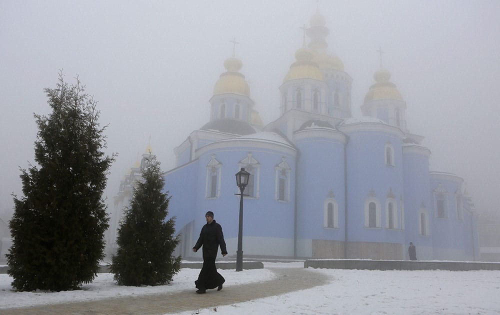 An Ukrainian clergyman passes a fog shrouded Mikhaylivsky Cathedral in central Kiev, Ukraine.