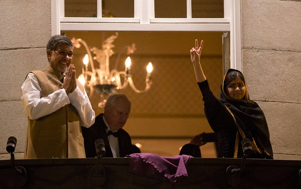 Nobel Peace Prize winners Malala Yousafzai from Pakistan and Kailash Satyarthi of India, left, respond to cheering and applause from a crowd of people as they stand on a balcony of their hotel before attending the Nobel Banquet in Oslo, Norway.