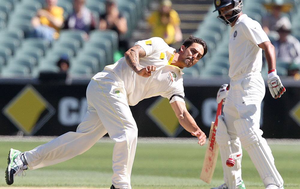 India's Shikhar Dhawan, right, watches as Australia's Mitchell Johnson fields on the wicket during the third day of their cricket test match in Adelaide, Australia.