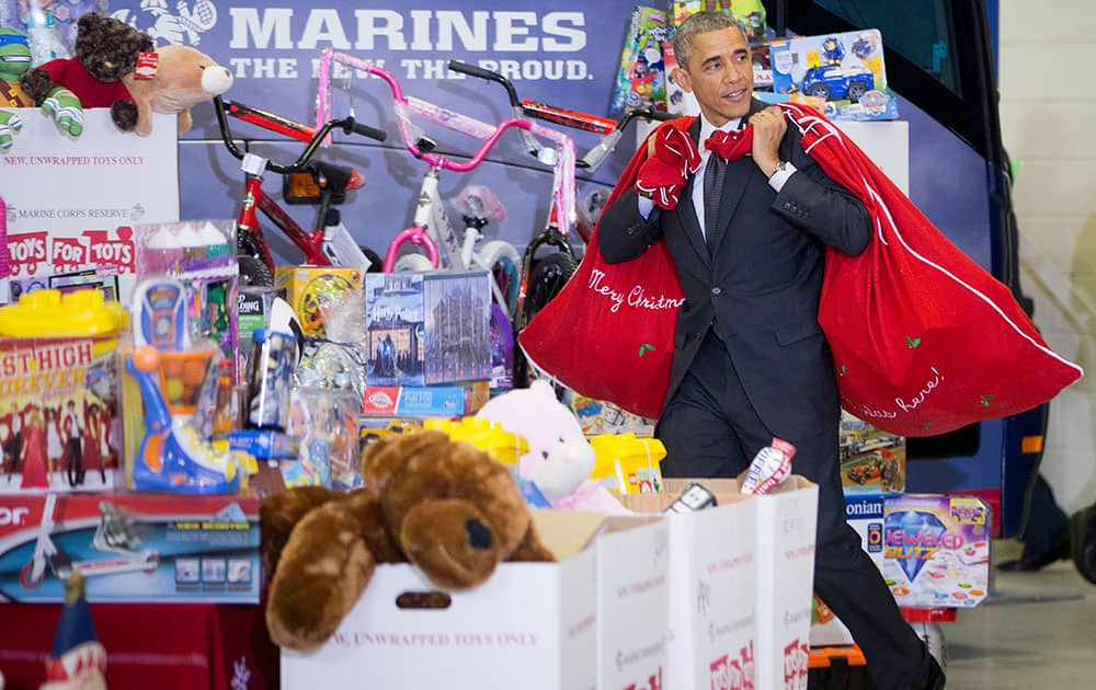 President Barack Obama carries two bags of gift bags over his shoulders as he arrives to help first lady Michelle Obama sort toys and gifts for the Marine Corps' Toys for Tots Campaign, at Joint Base Anacostia-Bolling in Washington. 