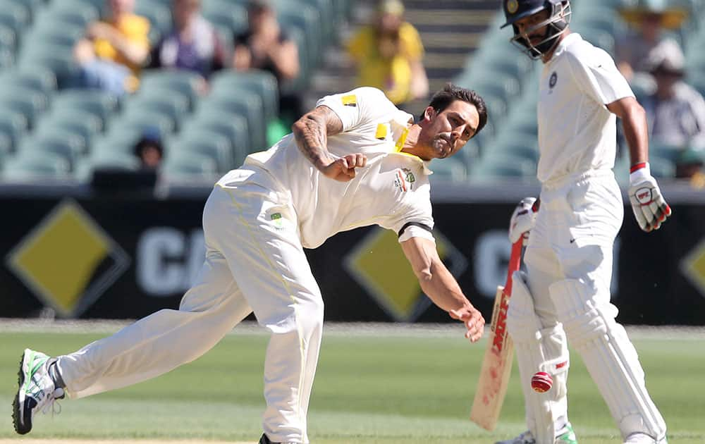 India's Shikhar Dhawan watches as Australia's Mitchell Johnson fields on the wicket during the third day of their cricket test match in Adelaide, Australia.