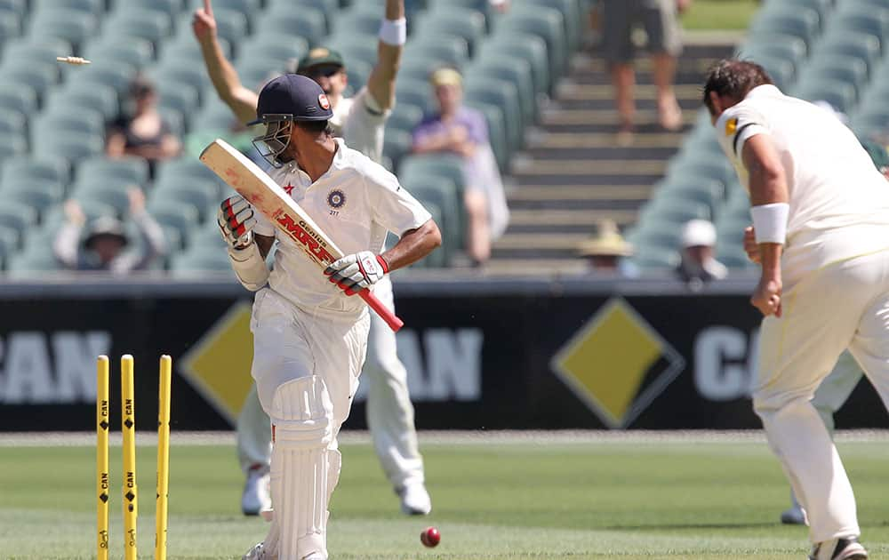 India's Shikhar Dhawan turns to see he is bowled by Australia's Ryan Harris during the third day of their cricket test match in Adelaide, Australia.