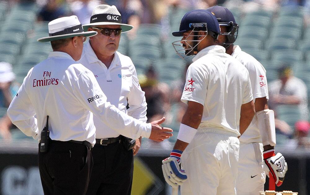 India's Virat Kohli is checked by the umpires, Ian Gould and Marais Erasmus after he was hit in the head by a bouncer from Australia's Mitchell Johnson during the third day of their cricket test match in Adelaide, Australia.