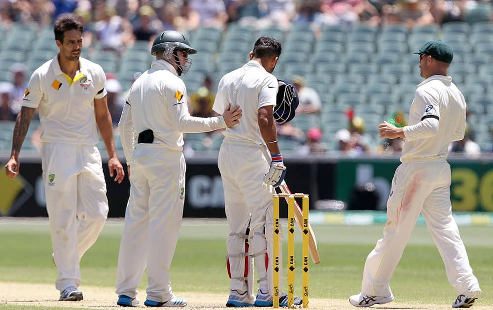 India's Virat Kohli is checked by Australia's Mitchell Johnson, Steve Smith and David Warner, after Kohli was hit in the head with a bouncer from Johnson during the third day of their cricket test match in Adelaide, Australia.