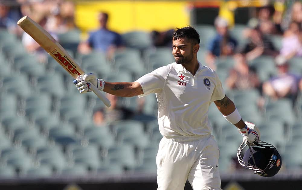 India's Virat Kohli raises his bat after making 100 runs against Australia during the third day of their cricket test match in Adelaide, Australia.