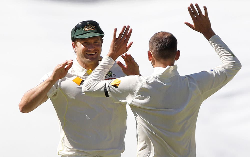 Australia's Shane Watson and Nathan Lyon celebrate after they combined to take the wicket of India's Ajinkya Rahane for 62 runs during the third day of their cricket test match in Adelaide, Australia.