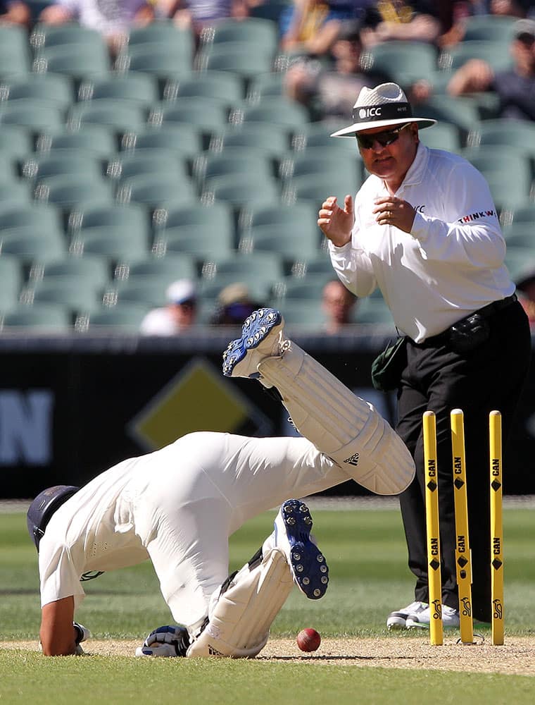 India's Rohit Sharma, dives back to his crease as umpire Marais Erasmus watches during the third day of their cricket test match against Australia in Adelaide, Australia.