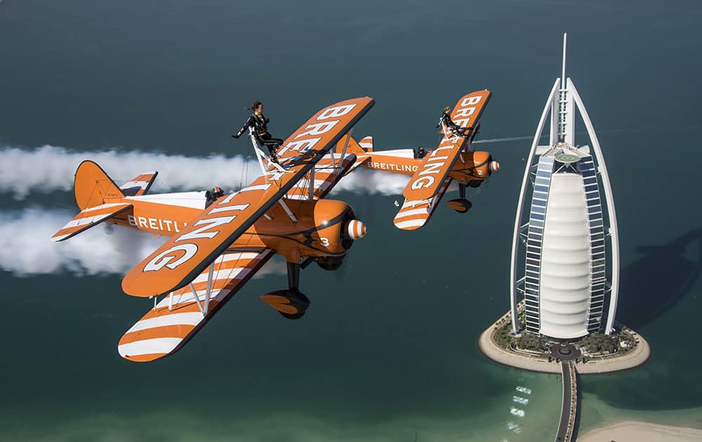 The British Breitling Wingwalkers, Danielle Hughes and Emily Guilding, soar past the Burj Al Arab in Dubai at 1,500 feet (460 meters) in excess of 100mp/h, ahead of their Dubai debut performance at the 2014 UIM Skydive Dubai XCAT World Powerboating Series.