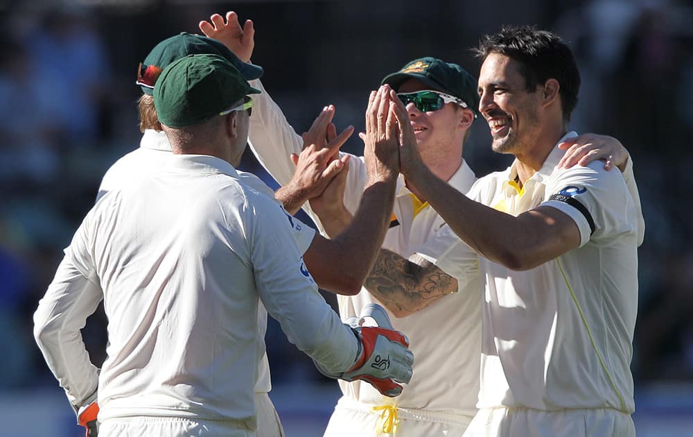 Australia's Mitchell Johnson, celebrates with teammates after taking the wicket of India's Virat Kohli for 115 runs during the third day of their cricket test match in Adelaide, Australia.