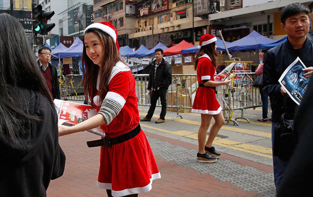 Two women in Santa constume deliver shopping leaflets in the Causeway Bay shopping district, outside an occupied area by pro-democracy protesters in Hong Kong. Traffic was back to normal Friday in Hong Kong's financial district after authorities demolished a protest camp at the heart of the city's 2 and a half month pro-democracy movement. 