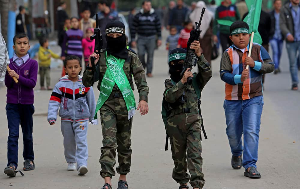 Palestinian boys wear green headbands with the Arabic, 'Ezz Al-Din Al Qassam brigade,' and green Islamic flag, while holding toy guns during a rally to commemorate the 27th anniversary of the Hamas militant group, at the main road in Jebaliya in the northern Gaza Strip.