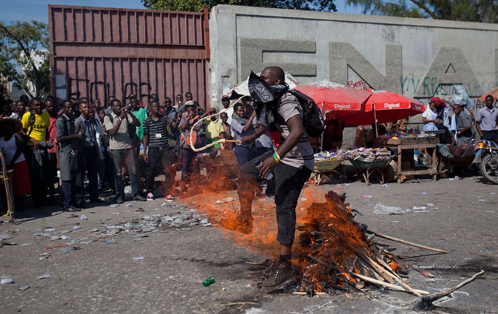 A demonstrator carrying a whip walks over fire in a voodoo ceremony at the start of a protest demanding the resignation of Haiti's President Michel Martelly and Prime Minister Laurent Lamothe in Port-au-Prince, Haiti.