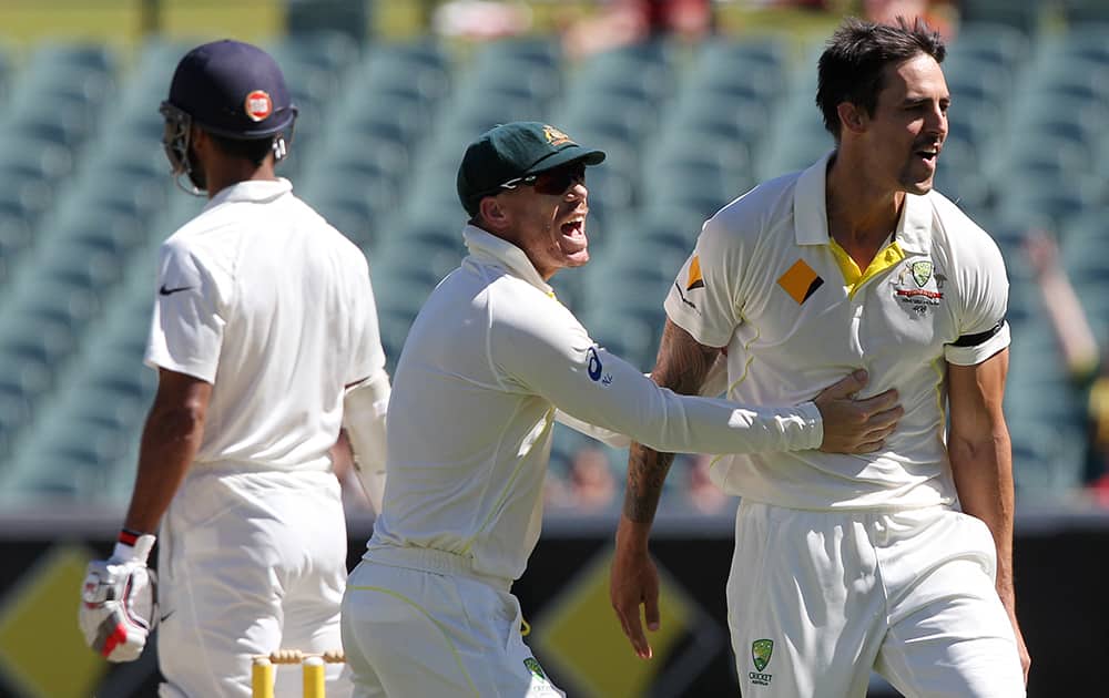 David Warner congratulates teammate Mitchell Johnson, after he dismissed Shikhar Dhawan, during the final day of their cricket test match in Adelaide, Australia
