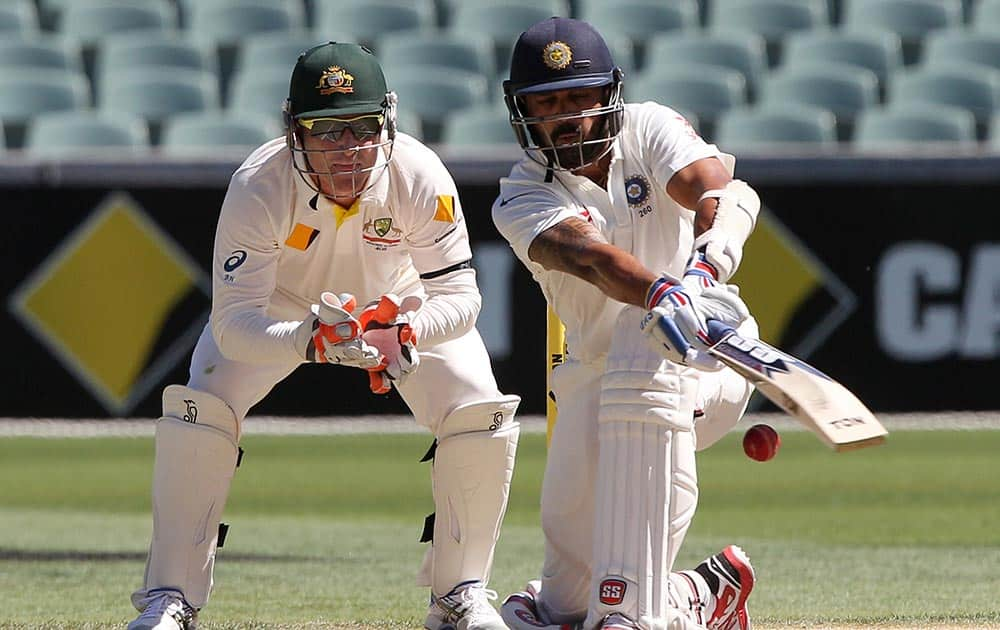 Murali Vijay plays a sweep shot as Australia's Brad Haddin, left, looks on during the final day of their cricket test match in Adelaide.