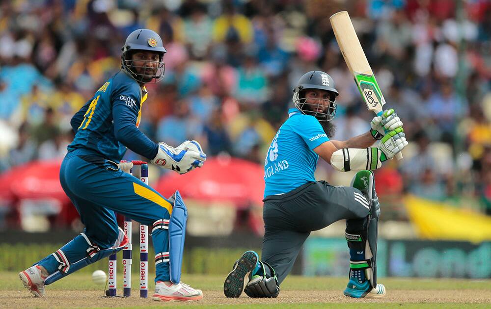 England's Moeen Ali, plays a shot as Sri Lankan wicketkeeper Kumar Sangakkara watches during the sixth one day international cricket match between Sri Lanka and England in Pallekele, Sri Lanka.