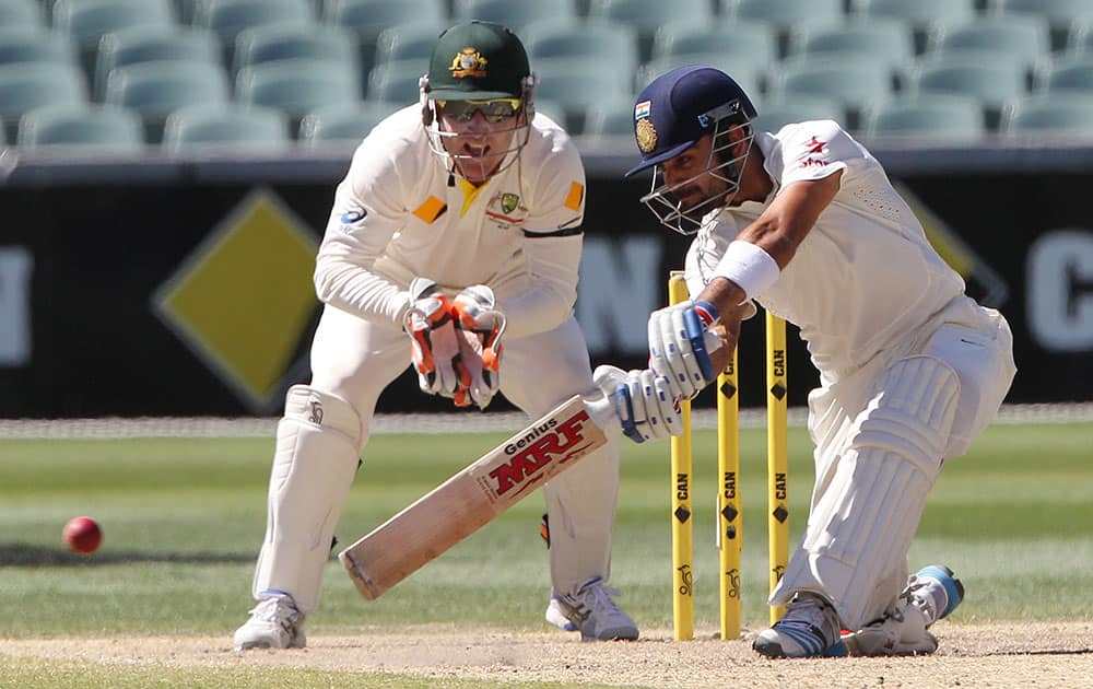 Virat Kohli plays a shot as Australia's Brad Haddin looks on during the final day of their cricket test match in Adelaide.