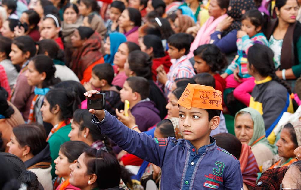 A young boy points his mobile phone towards the stage where Indian Prime Minister Narendra Modi is delivering a speech during an election campaign rally in Kathua, about 90 kilometers from Jammu.