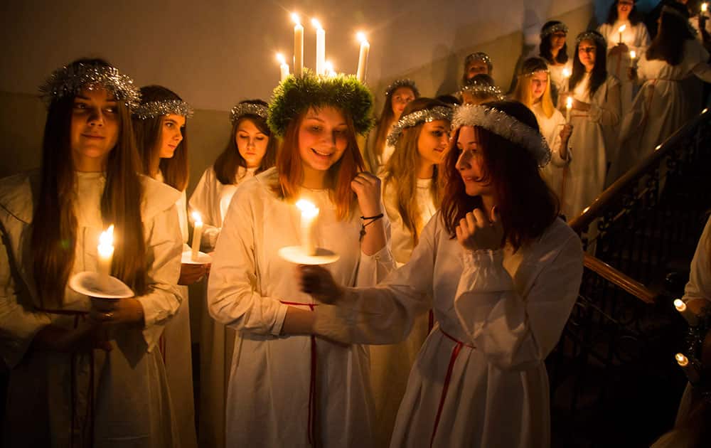 Young women hold candles as they prepare to walk in procession to celebrate St. Lucia's Day in the Evangelical Lutheran Church of Saint Katarina in St. Petersburg, Russia.