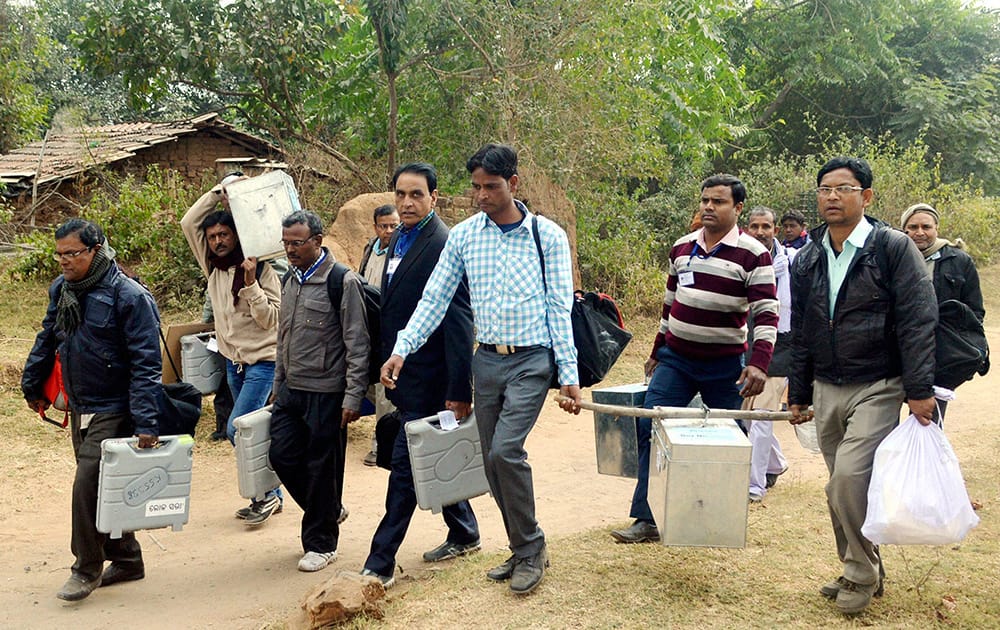 Polling staff carry EVMs as they leave for polling stations on the eve of 4th phase of Jharkhand assembly elections in Dhanbad.