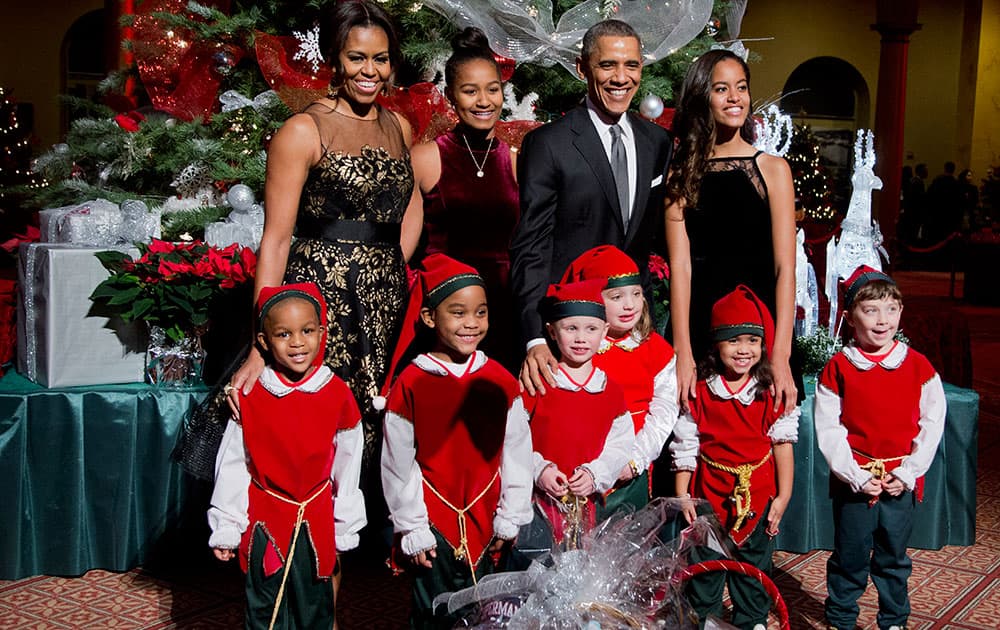 The first family, back from left, first lady Michelle Obama, Sasha Obama, President Barack Obama and Malia Obama, pose with children dressed like elves at the National Building Museum in Washington.