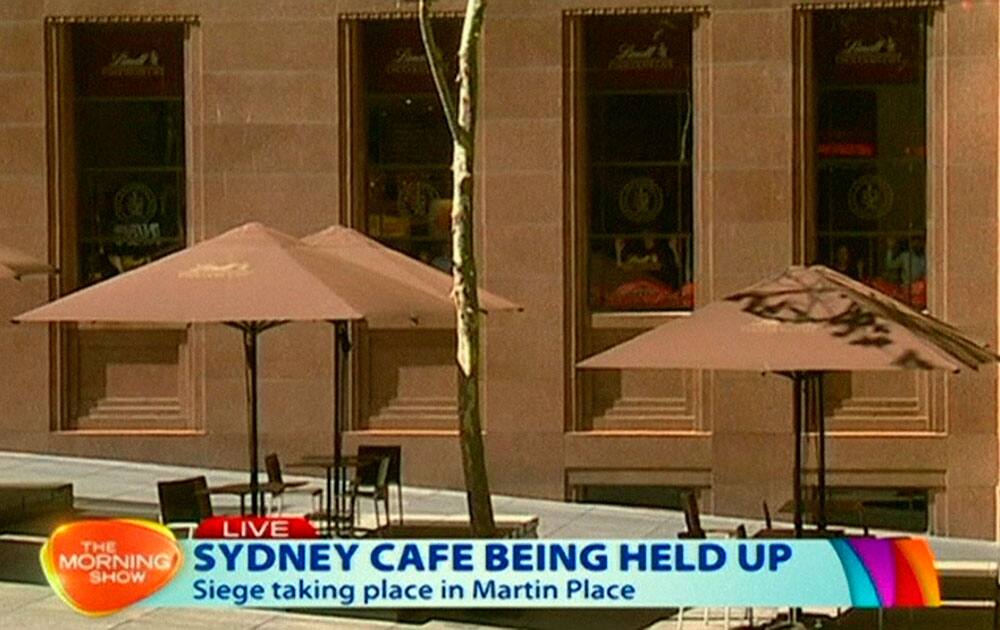 This image taken from video shows people against shop windows holding up hands inside a cafe in Sydney, Australia.