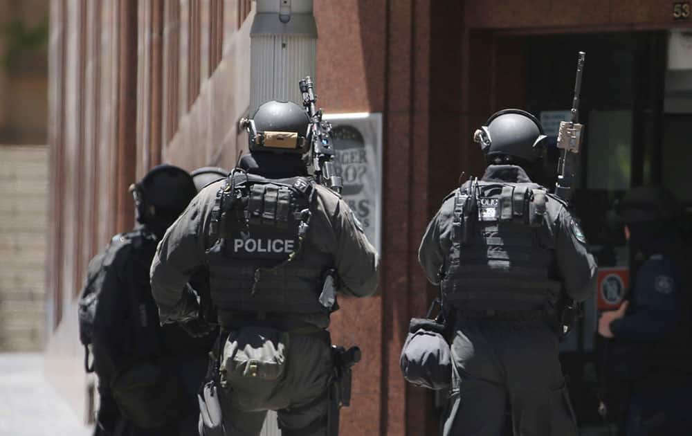 Armed police stand at the ready close to a cafe under siege at Martin Place in the central business district of Sydney, Australia.
