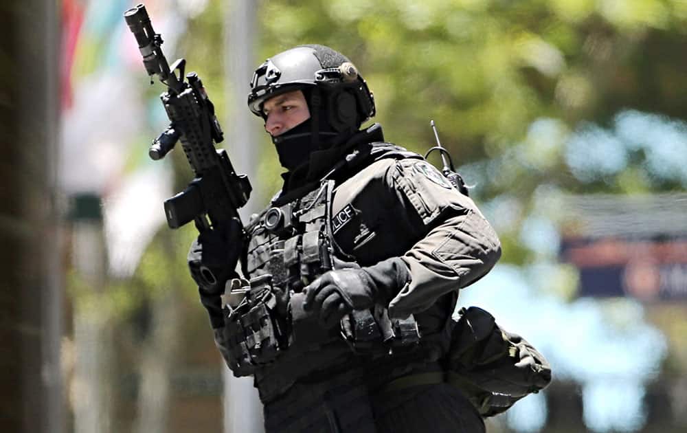 An armed police officer runs along the street close to a cafe under siege at Martin Place in the central business district of Sydney, Australia.