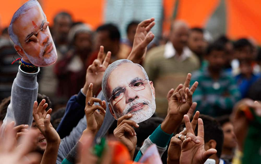 Supporter of India's ruling Bharatiya Janata Party (BJP) hold up masks of Prime Minister Narendra Modi during an election campaign rally in Kathua, about 90 kilometers from Jammu, India, Saturday, Dec.13, 2014.