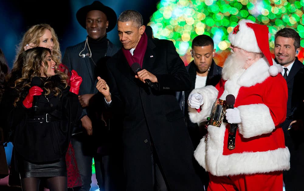 President Barack Obama dances on stage with Santa, members of Fifth Harmony, left, Chely Wright, Nico & Vinz and a member of The Tenors, behind, during the National Christmas Tree lighting ceremony at the Ellipse near the White House in Washington, Thursday, Dec. 4, 2014.
