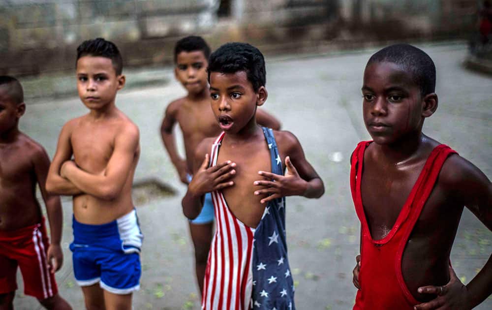 In his Oct. 15, 2014 file photo, 8-year-old Yodimiler Arias, along with fellow wrestlers, listen to instruction from their teacher, in a park in Old Havana, Cuba. Yodimiler's mother said the U.S. flag motif wrestling suit was sent by her cousin in the United States.