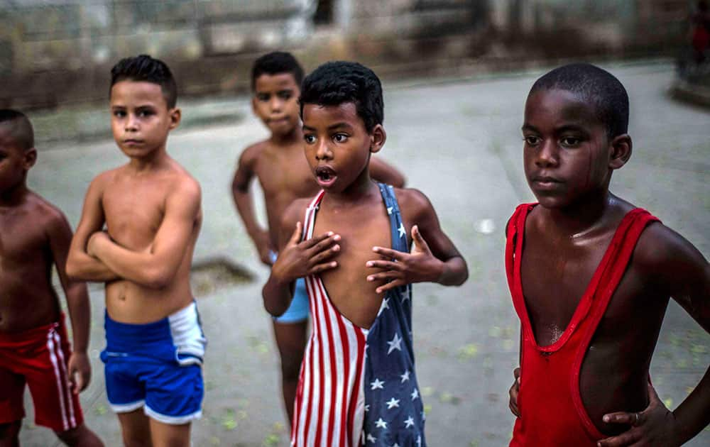 In his Oct. 15, 2014 file photo, 8-year-old Yodimiler Arias, along with fellow wrestlers, listen to instruction from their teacher, in a park in Old Havana, Cuba. Yodimiler's mother said the U.S. flag motif wrestling suit was sent by her cousin in the United States. 