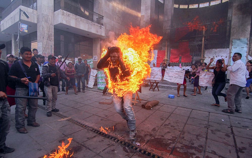 In this Dec. 5, 2014 file photo, farmer Agustin Gomez Perez runs engulfed in flames after he was lit on fire as a form of protest outside the Chiapas state legislature in Tuxtla Gutierrez, Mexico. Perez, 21, was demanding the release of his father, indigenous leader Florentino Gomez Giron, who was arrested last year on charges stemming from a series of demonstrations in 2011 that turned violent. 