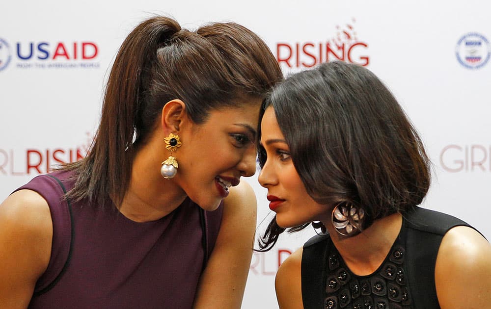 Bollywood actress and Girl Rising ambassador Priyanka Chopra, left, whispers into the ear of fellow ambassador and Hollywood actress Freida Pinto at the launch of Girl Rising: Engage India, in New Delhi, India, Saturday, Nov. 29, 2014.