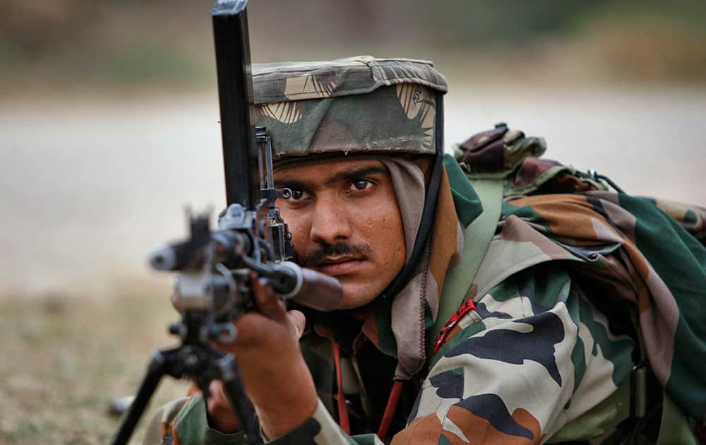 An Indian Army soldier takes position during an encounter with armed suspected militants at Pindi Khattar village in Arnia border sector, 43 kilometers (27 miles) south of Jammu, India, Thursday, Nov. 27, 2014.
