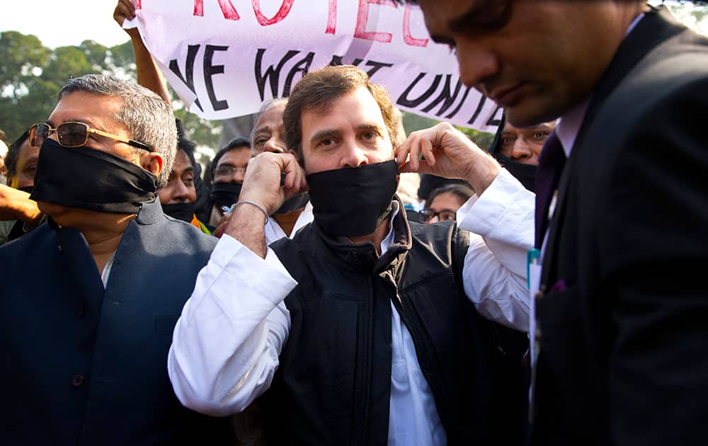 India's opposition Congress party Vice-President Rahul Gandhi, center, covering his mouth with a black cloth, participates in a protest outside the Indian Parliament in New Delhi, India, Friday, Dec. 5, 2014.