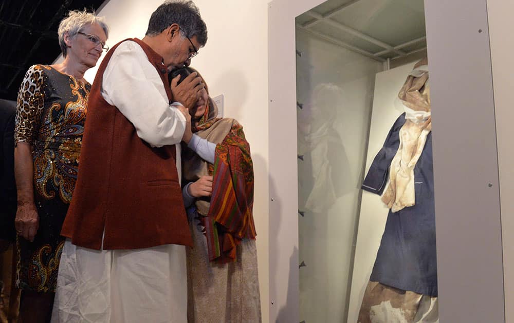 Prize winners Kailash Satyarthi and Malala Yousafzai, right, look at Malala's blood stained school uniform at the opening of the Nobel Peace Prize exhibition at the Nobel Peace Center in Oslo, Thursday, Dec. 11, 2014.