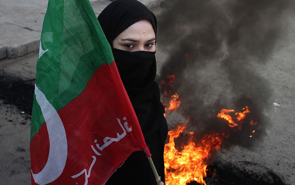 A female supporter of Pakistan's cricketer-turn-politician Imran Khan, leader of Pakistan Tehreek-e-Insaf blocks a main road during an anti-government protest in Lahore, Pakistan.