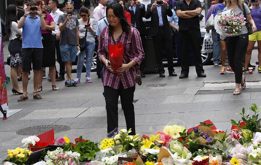 A WOMAN CRIES AS SHE VISITS A MAKESHIFT MEMORIAL IN SYDNEY, AUSTRALIA, NEAR WHERE THREE PEOPLE DIED IN A SIEGE. AN IRANIAN-BORN GUNMAN TOOK 17 PEOPLE HOSTAGE AT A CENTRAL CITY CAFE MONDAY BEFORE POLICE STORMED THE CAFE EARLY TUESDAY. THE GUNMAN AND TWO HOSTAGES WERE KILLED.
