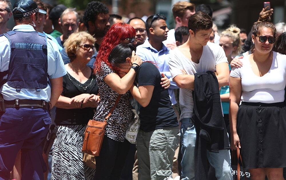 Employees of the Lindt Cafe comfort each other as they pay tribute to colleagues who lost their lives following the shootings at the coffee shop at Martin Place in the central business district of Sydney Australia.