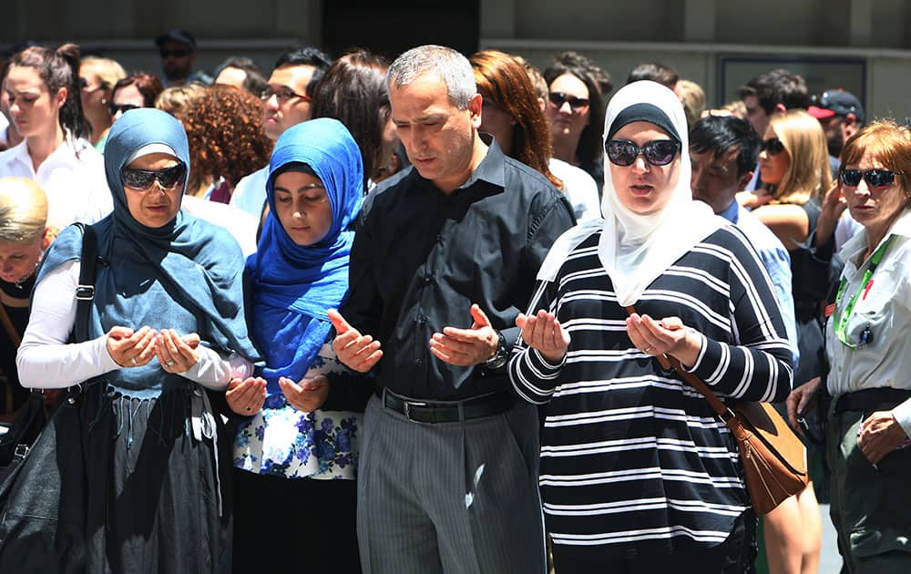 Sydney Muslim community leader Jamal Rifi, center, and his family members pray at a makeshift memorial after a siege at Martin Place in the central business district of Sydney, Australia.