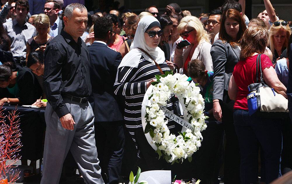 A Muslim woman carries a wreath of flowers as they pay respect to the shooting victims at a makeshift memorial at Martin Place at Martin Place in the central business district of Sydney, Australia.